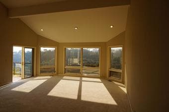 Large room with beautiful bay windows looking out into the sun 1